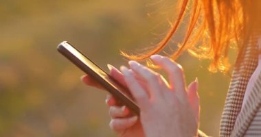 Dışarıda cep telefonu kullanan bir kadın, yakın plan. Elinde modern cep telefonu olan bir kadın.