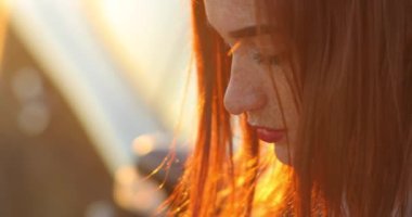 Kızıl saçlı, çilli genç bir kadının ciddi profilini yakın çekiyoruz..