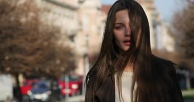 Çekici genç bayan ağaçlarla dolu sokakta yürüyor, kameraya bakıyor ve inanılmaz görünüşüyle büyülüyor. Güzel yeşil gözleri ve kumral uzun saçları olan muhteşem genç bir kadın.