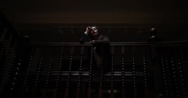 Hüzünlü atmosfer. Kahverengi paltolu üzgün esmer kadın bankta tek başına oturuyor ve tırabzana yaslanıyor. Üzgün bayan, karanlık koridorda evinde oturuyor. Yalnızlık kavramı