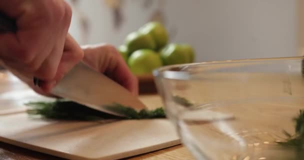 Primer plano mens manos cortan eneldo fresco. sobre el fondo del plato con las manzanas verdes. — Vídeo de stock