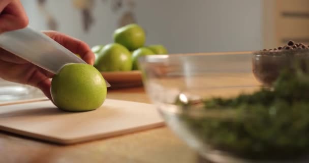 Крупним планом чоловічі руки вирізали свіже зелене яблуко. на фоні тарілки з кропом, перцевою картоплею з зеленими яблуками — стокове відео