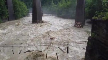 Yoğun yağmurlardan sonra güçlü bir akıntıyla kirli bir dağ nehri üzerindeki tahtadan köprü yıkıldı. Batı Ukrayna 'da sel. Tehlike. Element