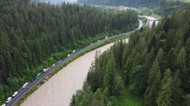Ormanla nehir arasındaki yol. Uzun süren yağmurlar nedeniyle birçok araba arazi kaymaları nedeniyle yola park edilmiştir.