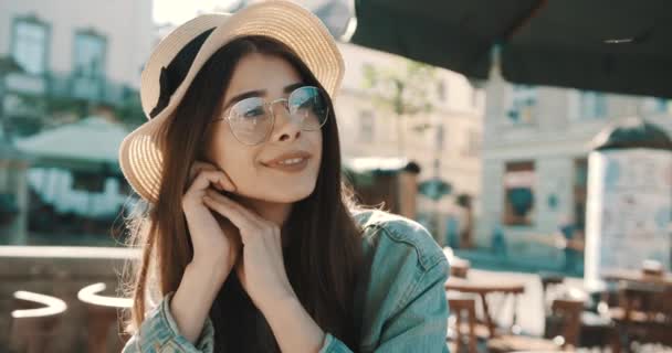 Close-up Retrato de mulher de moda de menina bonita bonita na moda posando na cidade na Europa, moda de rua de verão, segurando chapéu de palha rindo e sorrindo retrato. na moda — Vídeo de Stock