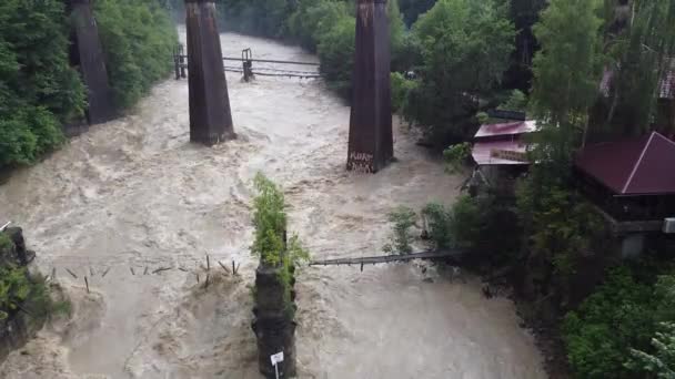 Ponte ferroviária pitoresca e uma ponte destruída sobre um rio de montanha tempestuoso entre montanhas verdes. Localização: Rio Prut, aldeia de Yaremche, Cárpatos, Ucrânia — Vídeo de Stock