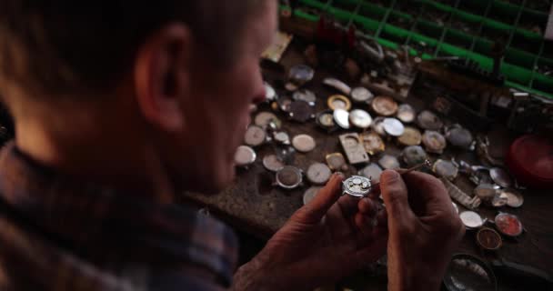 Hodinář je klenotník, monokl gravíruje detaily mechanismu starožitných zlatých hodinek ve své dílně — Stock video