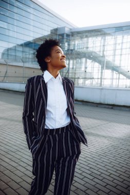 4 bin. Seyahat et, Dijital. Modern çizgili takım elbiseli çekici Afrikalı Amerikalı kadın cam duvarın yanında duruyor ve uçuşunu bekliyor. İş kadını ya da öğrenci