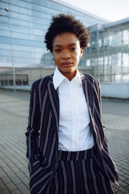 4 bin. Seyahat et, Dijital. Modern çizgili takım elbiseli Afro-Amerikan kadının portresi cam duvarın yanında duruyor ve uçuşunu bekliyor. İş kadını ya da öğrenci