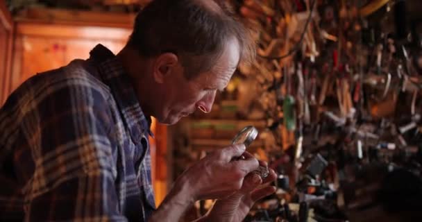 Saat ustası atölyede çalışıyor. Yaşlı büyücü eski kol saatini tamir ediyor. Bir büyüteçle usta — Stok video