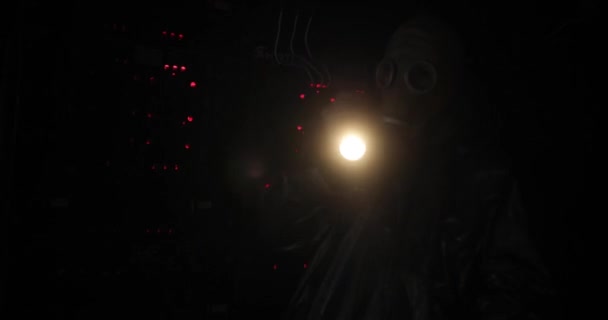Gaz maskeli ve tulumlu bir adam uzaktan kumandaya fener tutar. Kontrol panelinde kırmızı düğmeler yanıyor — Stok video