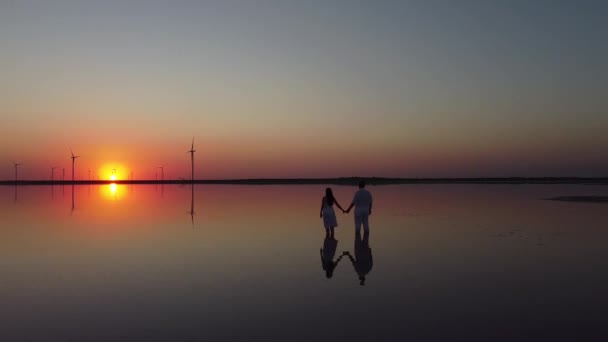 Silhouette eines verliebten Paares auf See in goldenem und schönem Sonnenuntergang. Junges und romantisches Paar genießen. Paar hält Händchen in goldener Sonne und wunderschönem Sonnenuntergang — Stockvideo