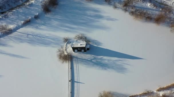 Sombra de um homem na neve caminhando para uma pequena casa de madeira. inverno, cabana solitária na neve. — Vídeo de Stock
