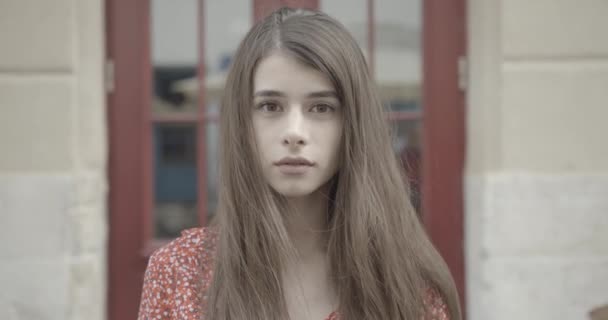 Portrait de la jeune femme adorable confiante aux longs cheveux foncés et aux yeux bruns regardant la caméra. Des images 4k. Gros plan. — Video