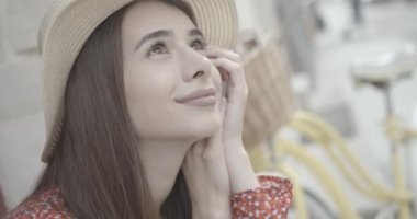 Şapkalı, başını kaldırıp gülümseyen huzurlu genç kadının portresi. Zevk duyguları. 4k görüntü.