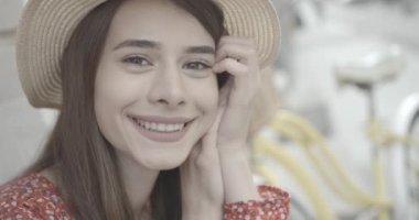 Koyu kahverengi gözlü güzel esmer kameraya gülümsüyor. O, şapka takıyor. 4k görüntü.