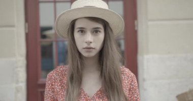 Kapının bulanık arka planına bakan şapkalı esmer kadının portresi. 4k.