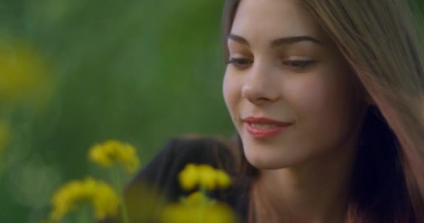 자연 화장 과예쁜 미소를 가진 아름다운 금발 여성의 부드러운 사진노란 꽃 냄새를 맡으며. — 비디오