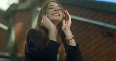 Doğal makyajı ve güzel gülüşü olan harika bir genç kız cep telefonuyla konuşuyor ve saçını dışarıda okşuyor..