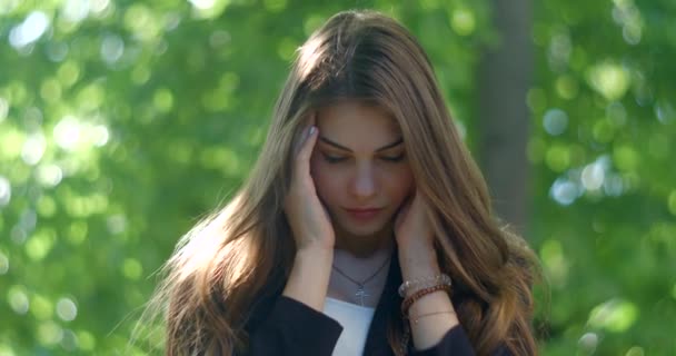 Retrato al aire libre de la encantadora chica deprimida molesta con el maquillaje natural que tiene el dolor de cabeza y preocupante. — Vídeos de Stock