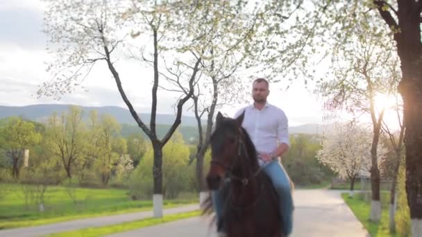 Joven con una camisa blanca montando un caballo — Vídeo de stock