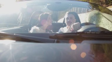 Sevgi dolu bir çift dağların arasında siyah bir araba kullanıyor. Çekici esmer kadın, arabasını kullanırken erkeğini öpüyor. Güzel manzaralar, yaz tatilleri.
