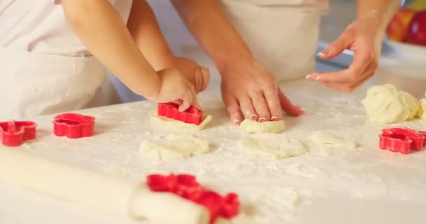 Vista de perto das mãos da mãe amassando a massa enquanto seu filho está usando os moldes de biscoito. — Vídeo de Stock