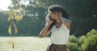 Hoş gülüşü ve yeşil göz farı olan güzel Afro-Amerikalı kız dans ediyor ve kulaklıktaki müziğin tadını çıkarıyor. Açık konum.