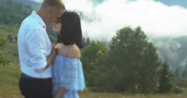 Romantik açık hava portresi dağların arka planında el ele tutuşan ve kucaklaşan genç çiftin.