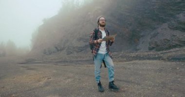 Dağlarda geziyorum. Şık sakallı genç adam dağda kalın bir sis ile kaplı eski bir haritayı öğreniyor.