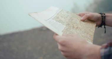 Dağlarda geziyorum. Ormanda sisle kaplı dururken eski harita erkeklerin elinde.