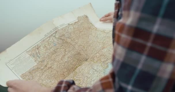 Bepergian di pegunungan. Old map in mans hands while he stands in the forest covered with thick fog — Stok Video