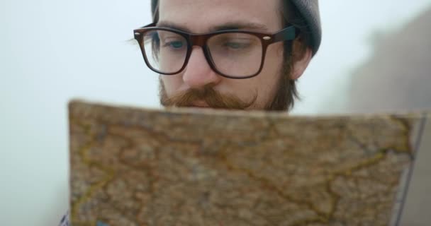 Bepergian ke pegunungan. Pria berkacamata memegang peta tua sebelum matanya berdiri di hutan tertutup kabut tebal — Stok Video
