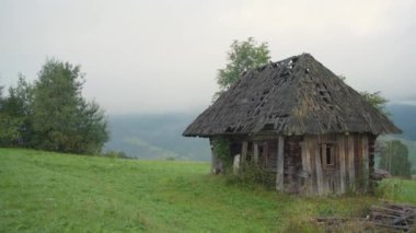 Resimli Carpathian dağlarının arka planında çobanlar için terk edilmiş eski ahşap bir ev. Terk edilmiş bina kötü durumda. Orman dağındaki eski ahşap ev. Ahşap ev ve...