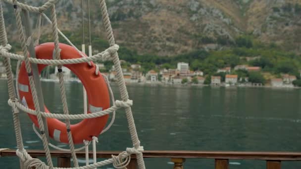 Lifebuoy on wooden stand on background of houses on the shore and mountains. — Vídeos de Stock