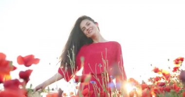 Güzel bir kadın saçlarını gelincik çiçeklerinin arasında sağa sola sallıyor. Çekim çekici bir genç bayanın altında, büyüleyici bir gülümsemeyle yapılıyor. Portre görüntüsü, beyaz gökyüzü, güneşli gün ve haşhaş tarlası..