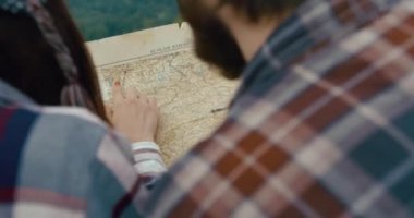 Dağlara seyahat edin genç adam ve kadın bir harita öğrenin ve bir kayanın tepesinden dağlara bakın..