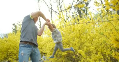 Mutlu aile portresi Mutlu baba etrafında dönen küçük oğlu sarı çiçek bahçesinde