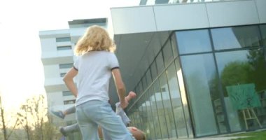 Beautiful smiling mother is holding her happy son and spinning him round near the modern building. Happy family concept in 4k