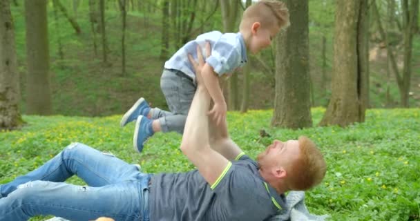 Happy Father Raising Spinning His Smiling Little Son While Lying — ストック動画
