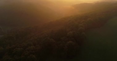Aerial drone flight over thick forests covering the foggy mountains during the sunset in Heilbronn, Germany. 4k footage