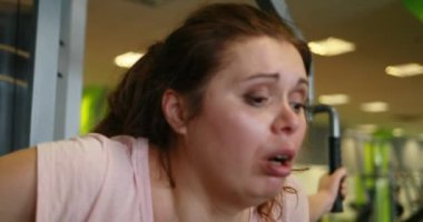 The sad crying obese woman is very disappointed and tired after working out on the pec deck training machine in gym