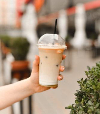 Elinde pipetle buzlu kahve.