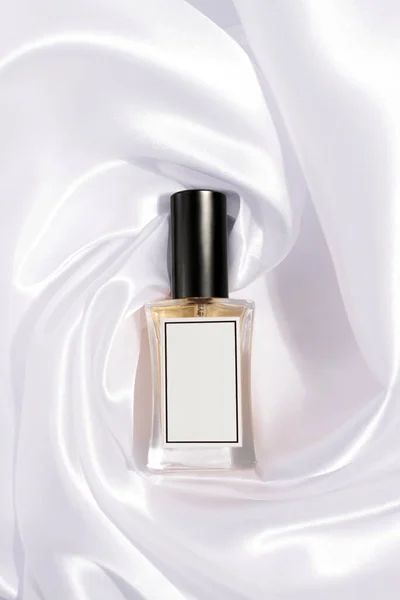 Beyaz ipek arka planda parfüm şişesi
