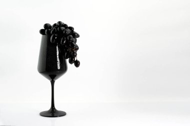 Beyaz üzerine siyah şarap kadehinde koyu üzüm.