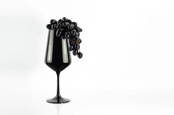 Beyaz üzerine siyah şarap kadehinde koyu üzüm.
