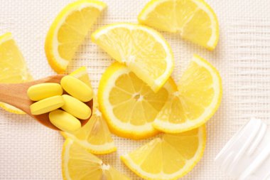 Vitamin hapları kaşıkta Limon dilimleri masada