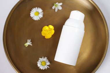 Beyaz plastik kozmetik şişesi bakır plaka, çiçekler, maket