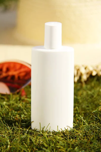 Sunscreen solar protection cream with sunglasses and straw hat on green grass, tropical sunny day