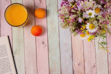 Kahvaltı masası, meyveler, meyve suyu kitabı ve çiçekler, renkli arka plan.